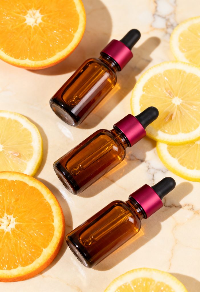 Vitamin C serum bottles with citrus slices on marble