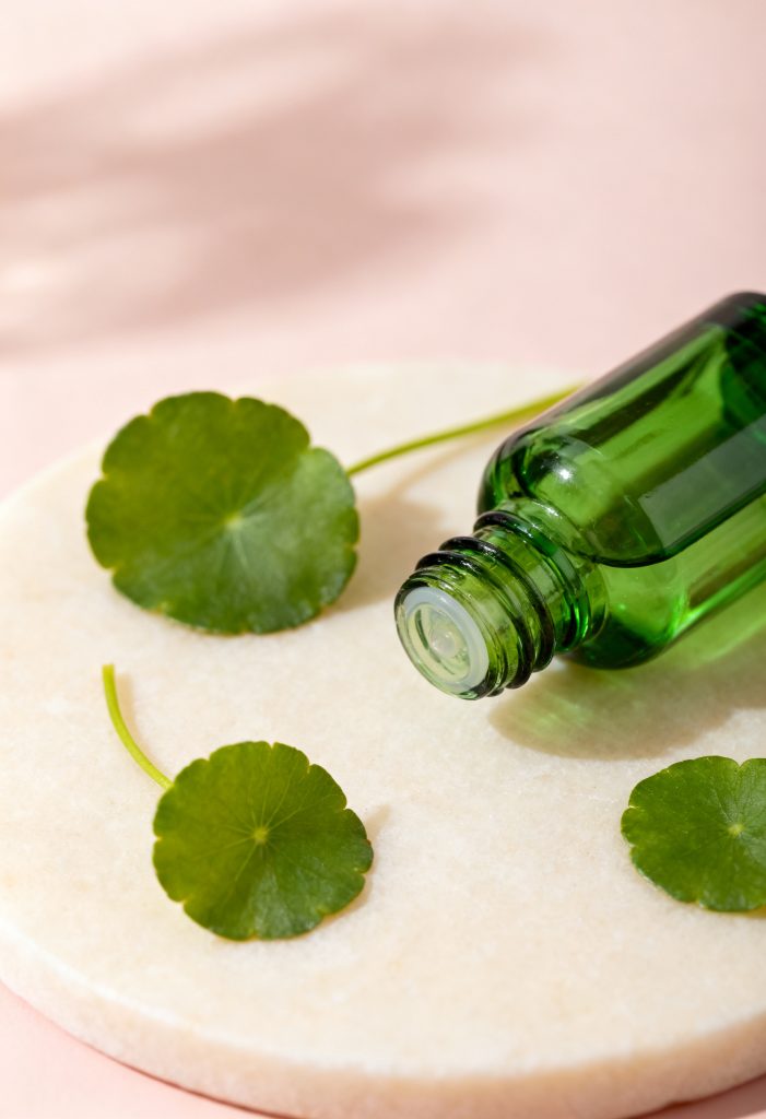 Centella asiatica leaves beside a green serum bottle